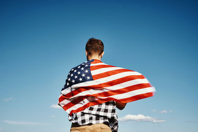 American flag outdoors. man holds usa national flag against blue cloudy sky. 4th july