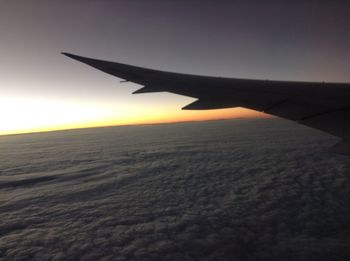 Airplane wing over landscape against clear sky