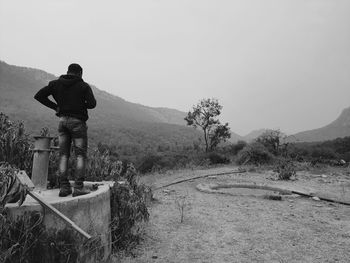 Rear view of man standing on mountain against clear sky