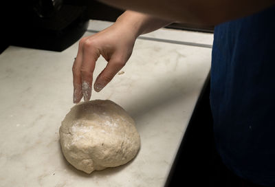 Cropped hand kneading dough on table