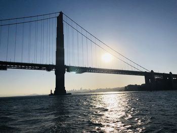 View of suspension bridge over river at sunset