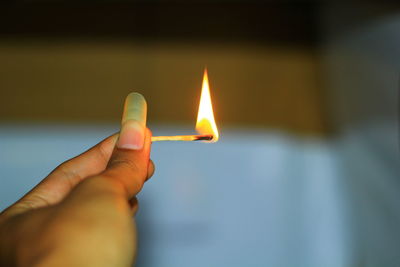 Cropped hand holding burning matchstick