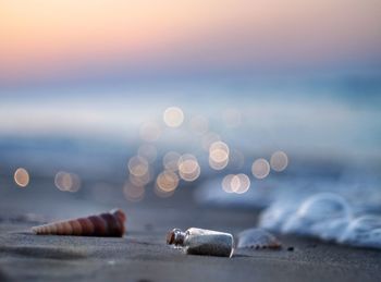 Close-up of cigarette at beach against sky during sunset