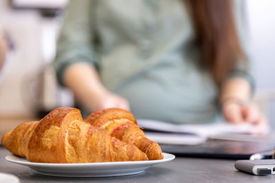 Fresh croissants on the background of a pregnant woman in a blur. no face.  diet food concept