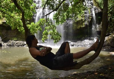 Man surfing in sea against trees in forest