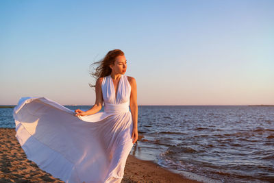 Woman on beach against sky during sunset