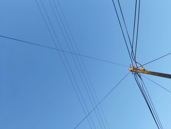 Low angle view of power lines against blue sky