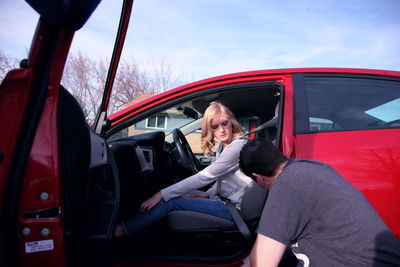 Side view of woman sitting in car against sky