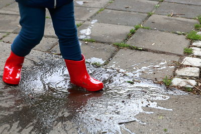 Low section of person splashing water while walking on wet footpath