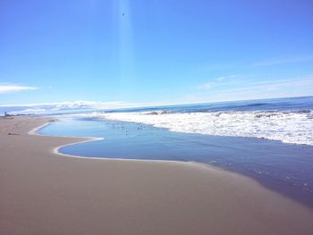 Scenic view of beach against blue sky