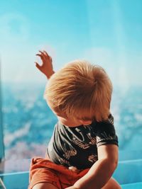 Baby boy sitting against glass window