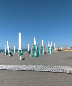 Deck chairs on beach against clear blue sky