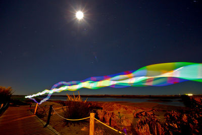 Light trails above boardwalk at night