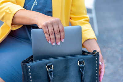 Unrecognizable white business woman saving her laptop in her handbag