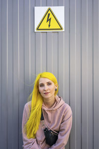 Portrait of young woman standing against wall