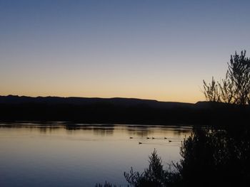 Scenic view of lake against clear sky during sunset