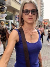 Portrait of young woman wearing sunglasses standing in city