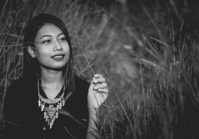 Young woman sitting amidst grass on field