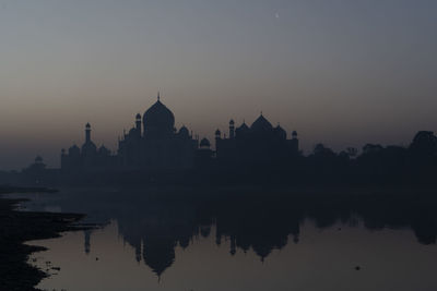 Taj mahal reflected in yamuna river at sunset in agra, india.