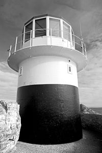 Low angle view of lighthouse by building against sky