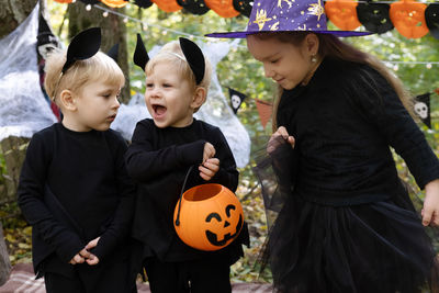 Happy kids in halloween costumes having fun in halloween decorations outdoor