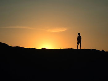 Silhouette man standing on mountain against sky during sunset