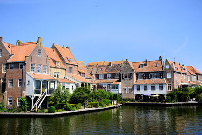 Buildings by river against blue sky