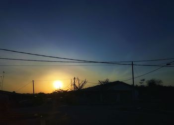 Silhouette houses against sky during sunset