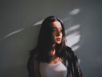 Portrait of young woman standing against wall