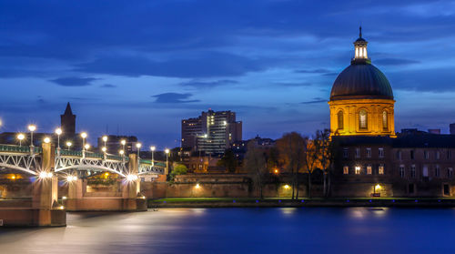 Illuminated hopital de la grave and bridge against sky at dusk