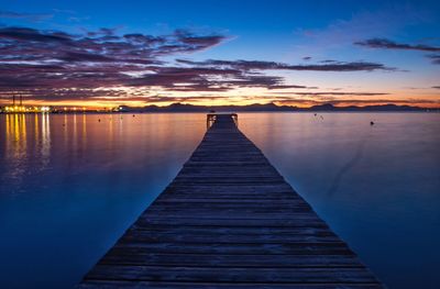 Pier over lake against sky during sunset