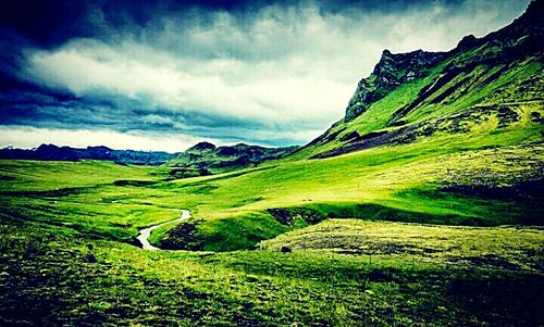 Scenic view of grassy field against cloudy sky