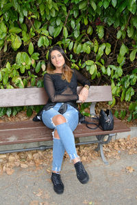 Portrait of smiling young woman sitting on sitting against plants