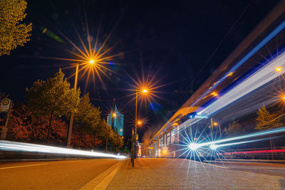 Illuminated light trails on road against sky at night