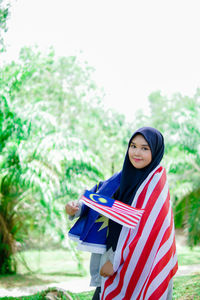 Muslim woman happy holding a malaysian flag. malaysia independence day.