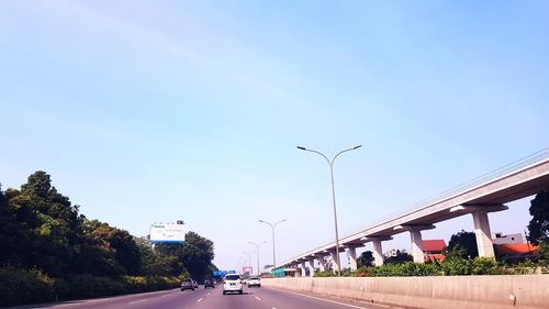 Vehicles on road against clear sky