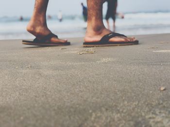 Surface level of man wearing flip flop at beach