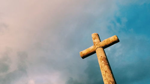 Low angle view of rusty cross against cloudy sky