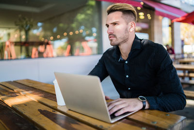 Young man using mobile phone while sitting on table