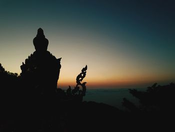 Silhouette statue against sky during sunset