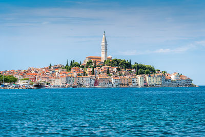 View of buildings by sea against blue sky