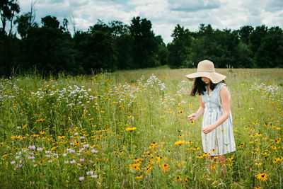 Girl wearing a floppy sun hat picking flowers in southern michigan