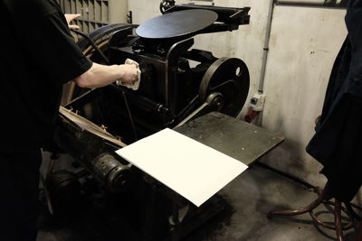 Midsection of typesetter using machinery while working in workshop