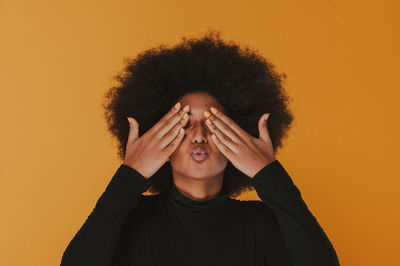 Portrait of beautiful young woman standing against orange background