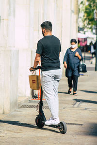 Full length rear view of man walking on footpath