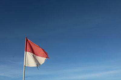 Low angle view of flag against blue sky