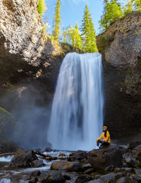 Rear view of man standing against waterfall