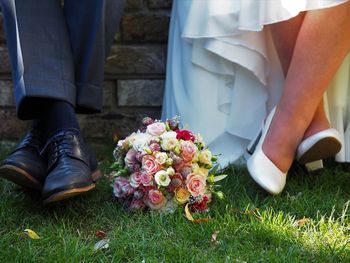 Low section of couple with flower bouquet on lawn