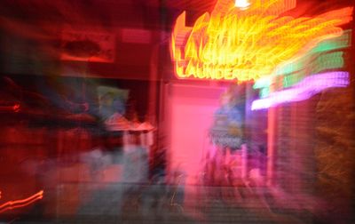 Defocused image of illuminated neon sign on window display of shop