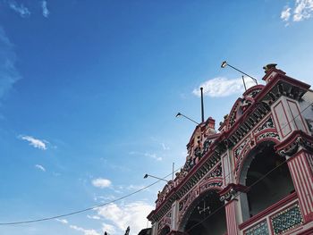 Low angle view of birds perching on building against sky